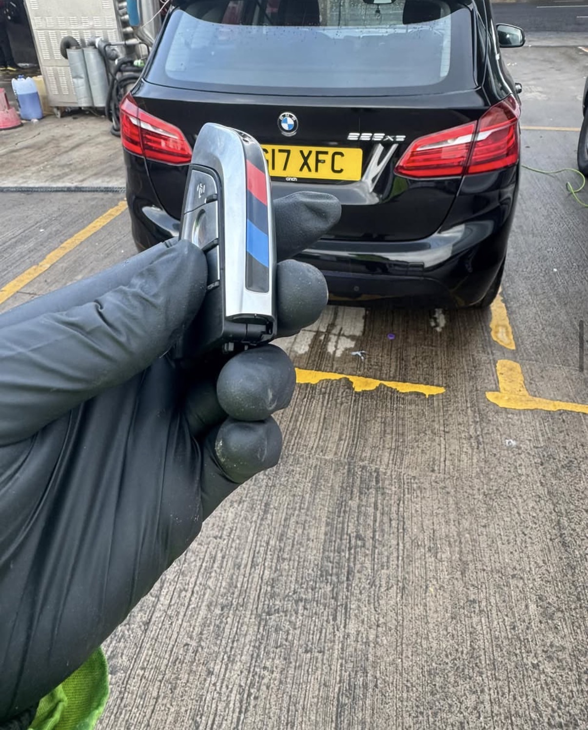 New BMW key held in front of a black BMW 2 Series