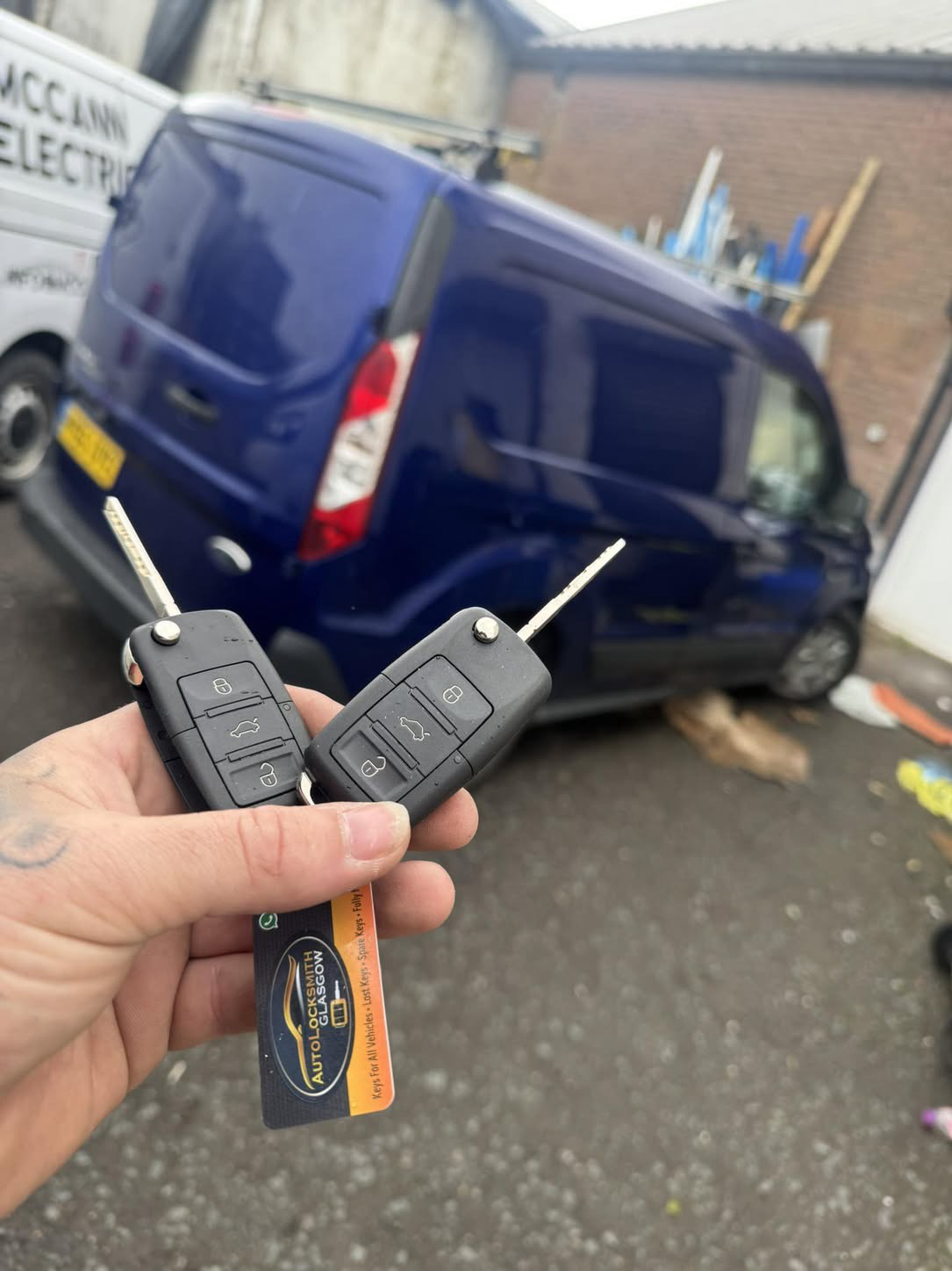Two Ford keys held in front of a blue Ford Transit Custom