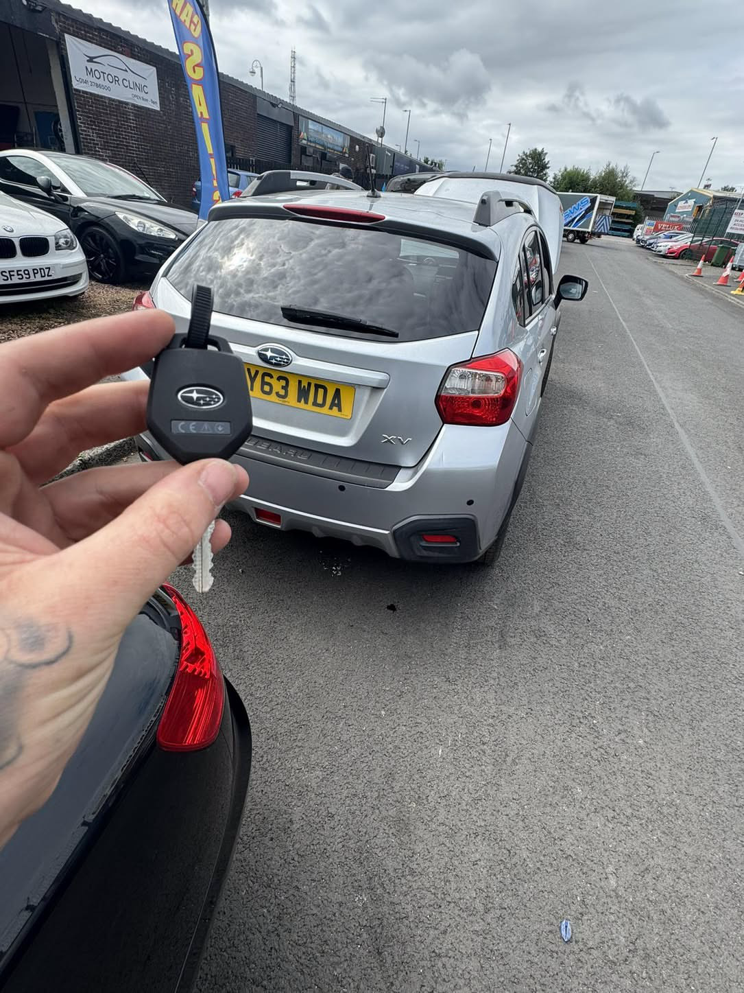 Subaru key held in front of a silver Subaru XV