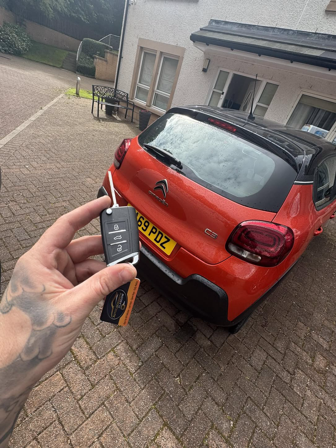 Citroën key held in front of a red Citroën C3