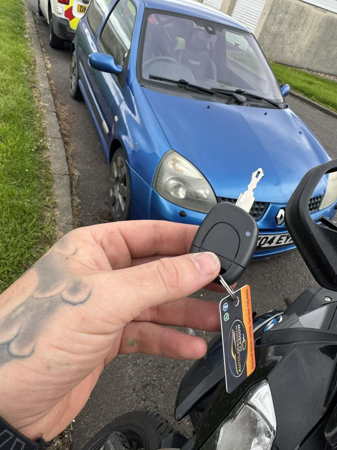 Renault key held in front of a blue Renault Clio