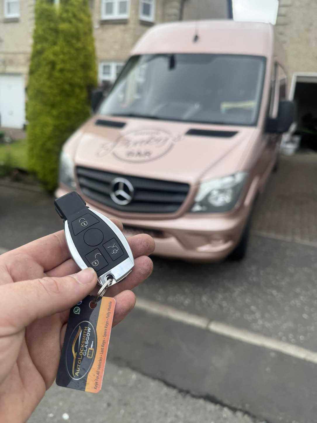 Mercedes key held in front of a Mercedes Sprinter van