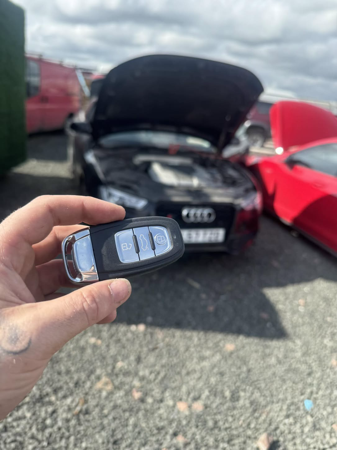 Audi key held in front of a black Audi