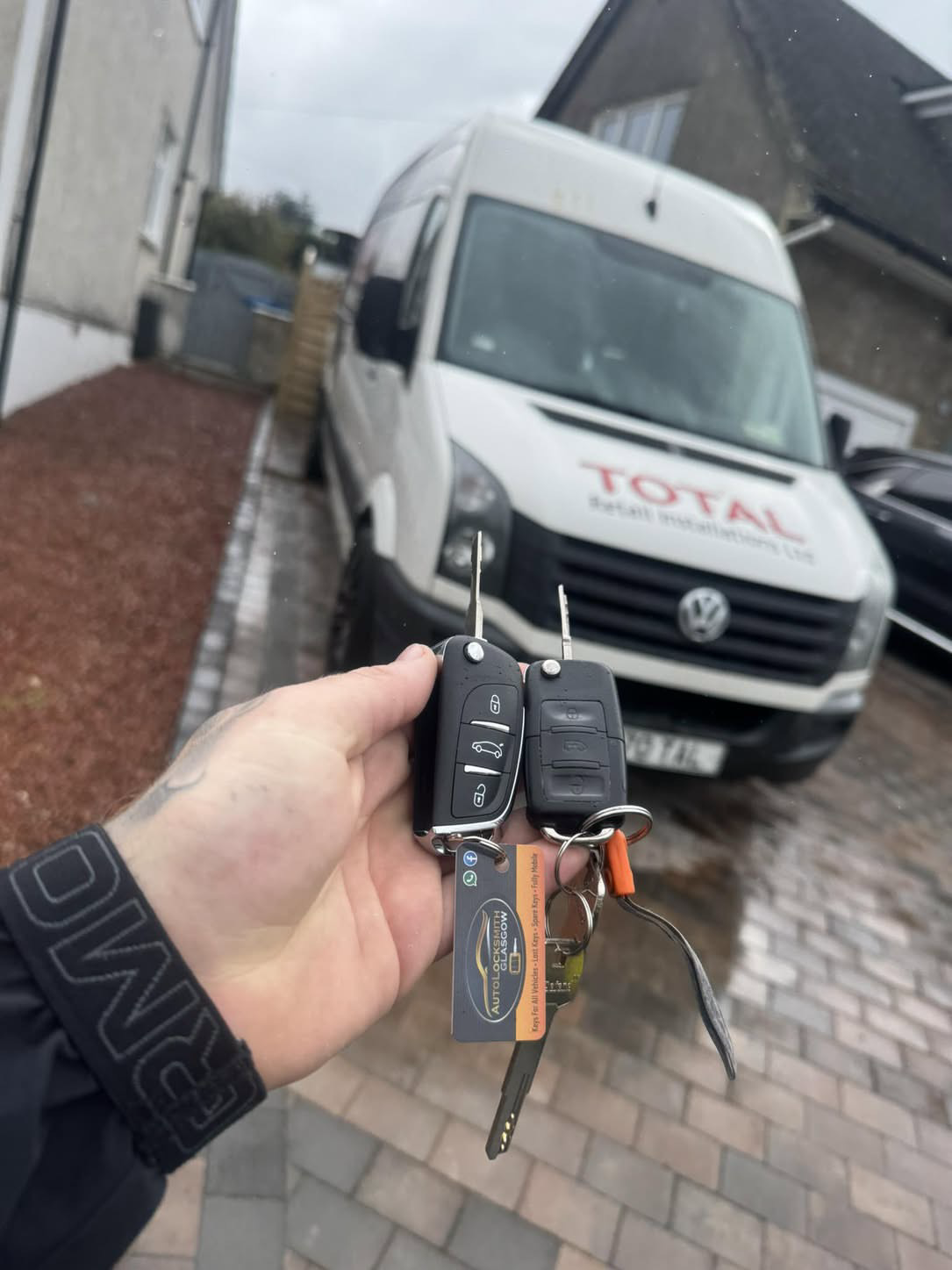 Two Volkswagen keys held in front of a white Volkswagen Crafter van