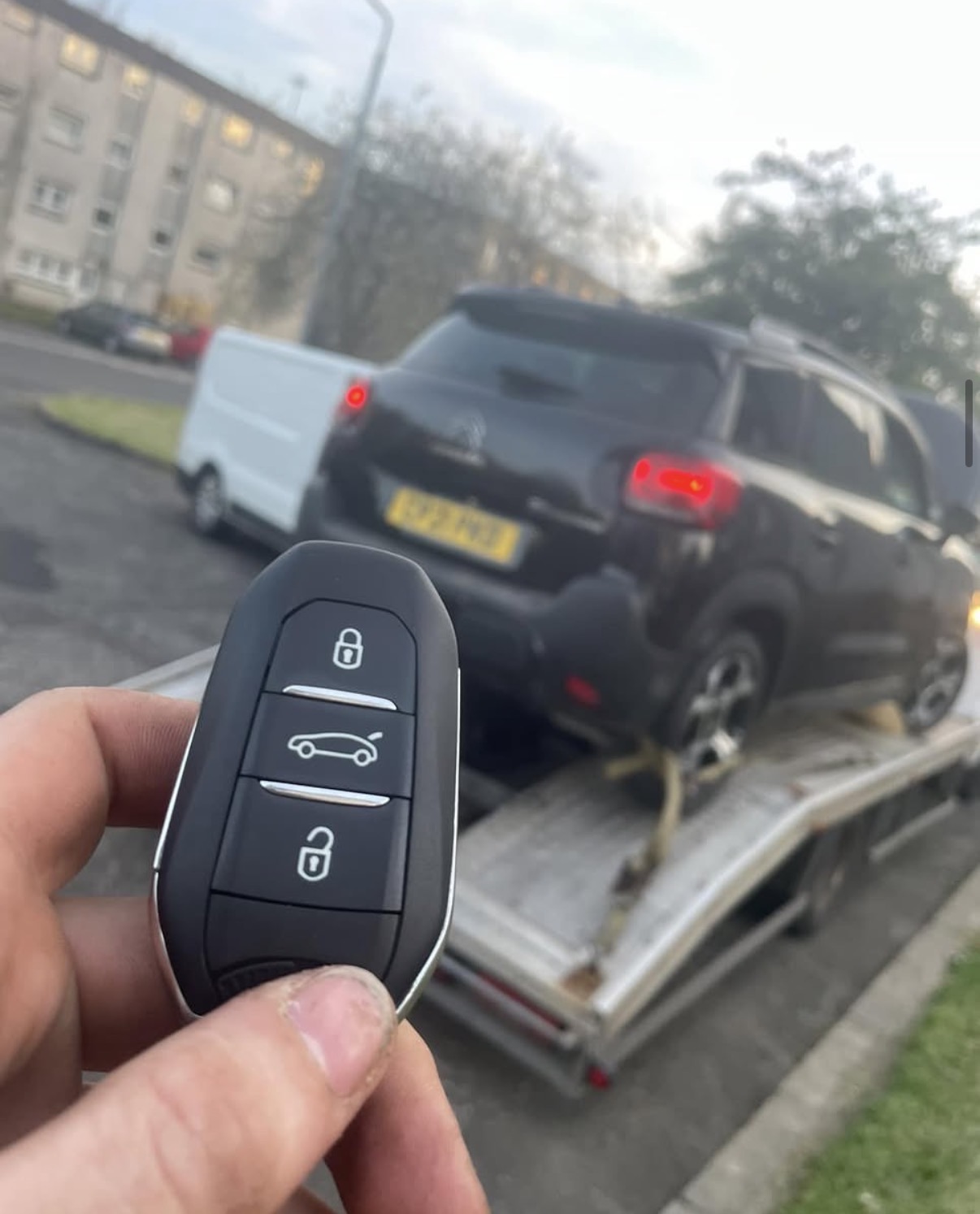 New Citroën key in hand with a Citroën C3 Aircross on a recovery truck behind