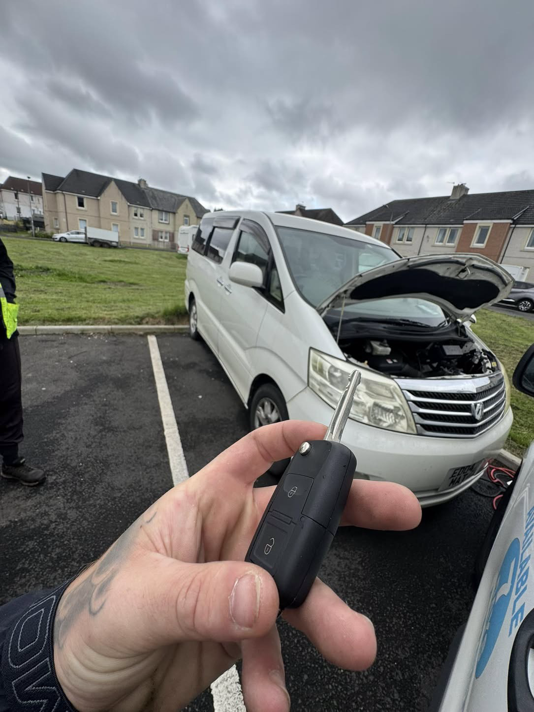 Toyota key held in front of a white Toyota Alphard